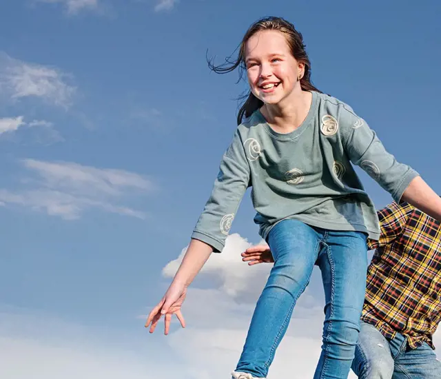 A man and a child jumping on a wooden board in a field.