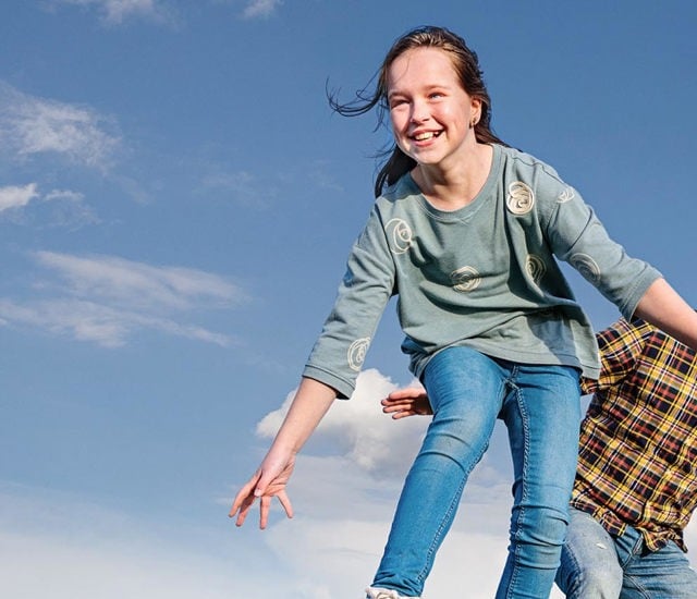  A man and a child jumping on a wooden board in a field.