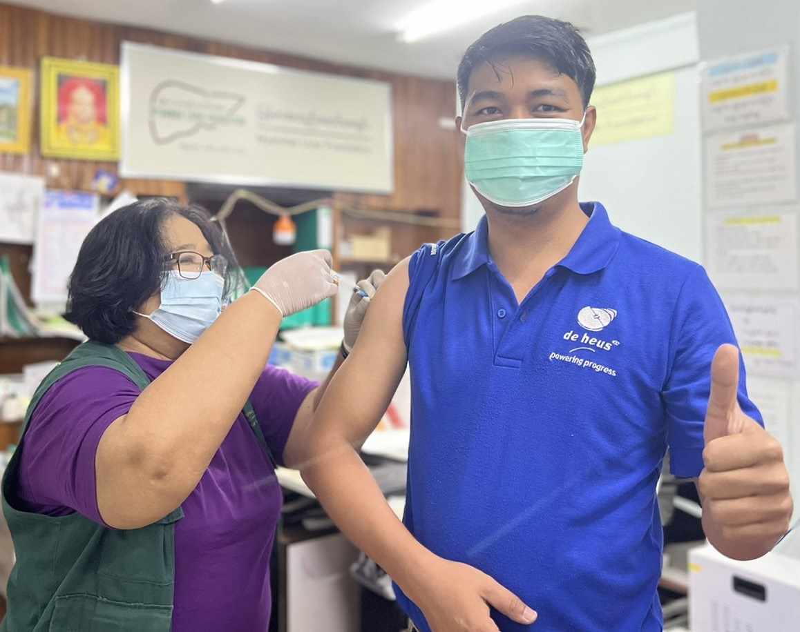 a doctor is vaccinating to a man and that man is thumb up and smiling